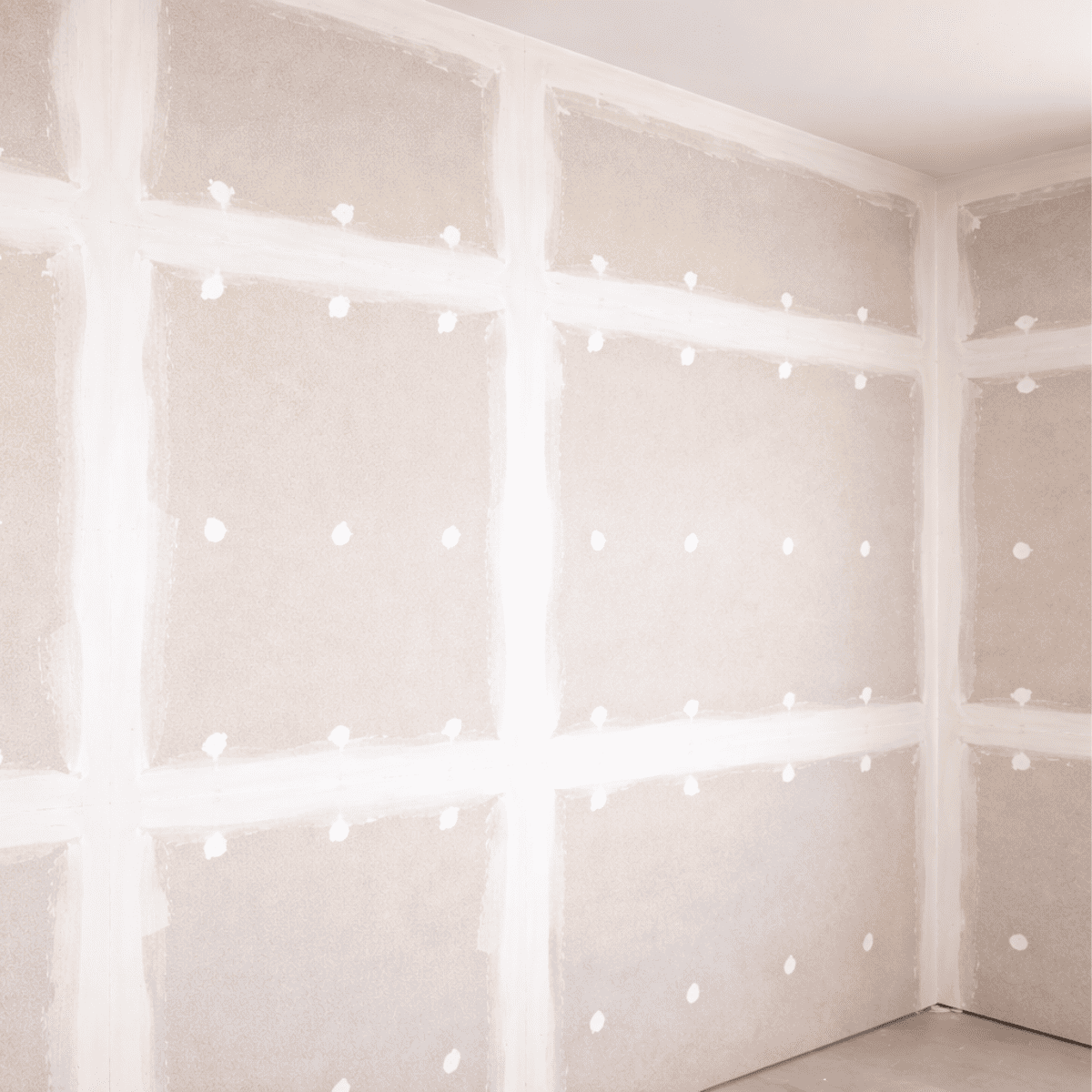 壁の下地として施工された石膏ボードの室内写真。ボードの継ぎ目にはパテ処理が施され、ビス固定された部分が白い点状で規則的に並んでいる。