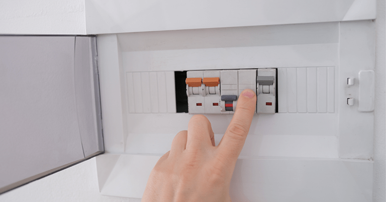 手でブレーカーのスイッチを操作している様子。壁紙DIY作業前に電源を切る安全確認のシーン。