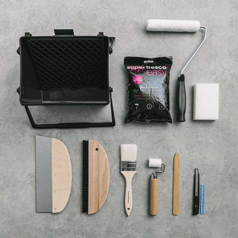 壁紙DIY用の施工道具一式。ローラー、バケット、刷毛、パテベラ、カッター、刷毛などを並べたセット