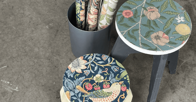 ウィリアム・モリス柄の壁紙を貼った丸いスツールと、同柄の壁紙ロールを入れた筒状ケースがコンクリート床に置かれたDIYコーディネート例