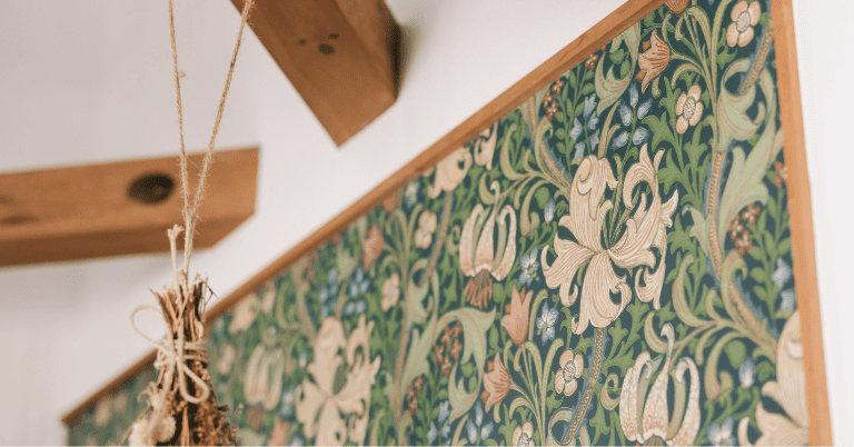 ウィリアム・モリスのボタニカル柄壁紙を壁に施工した様子。グリーンを基調に花や植物模様が描かれ、木製の梁やドライフラワーが飾られている