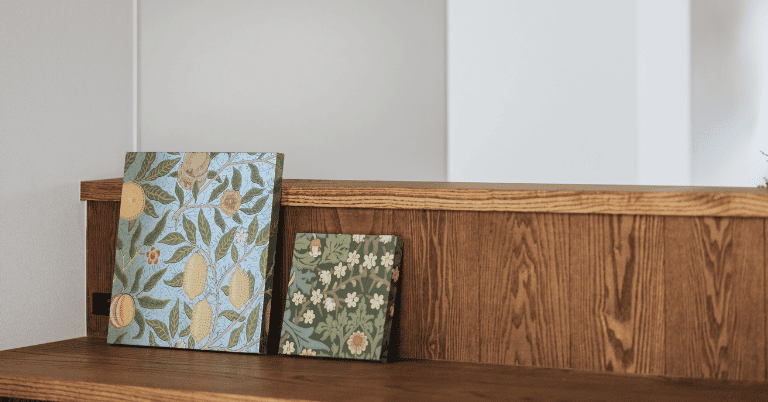 ウィリアム・モリス柄の壁紙サンプルパネルを木製カウンターに立てかけている様子。レモン柄と小花柄のデザイン見本