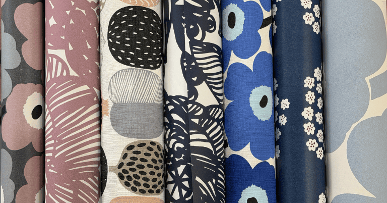 様々な色と柄のマリメッコ風デザインの壁紙ロールが並んでいる様子。花柄や抽象模様が特徴的。